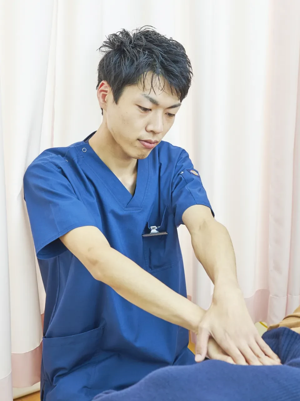 施術者が患者の脚に手を当てて状態を確認している様子